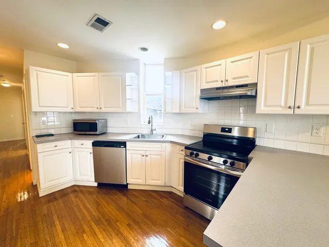 a kitchen with stainless steel appliances granite countertop a stove a sink and a microwave
