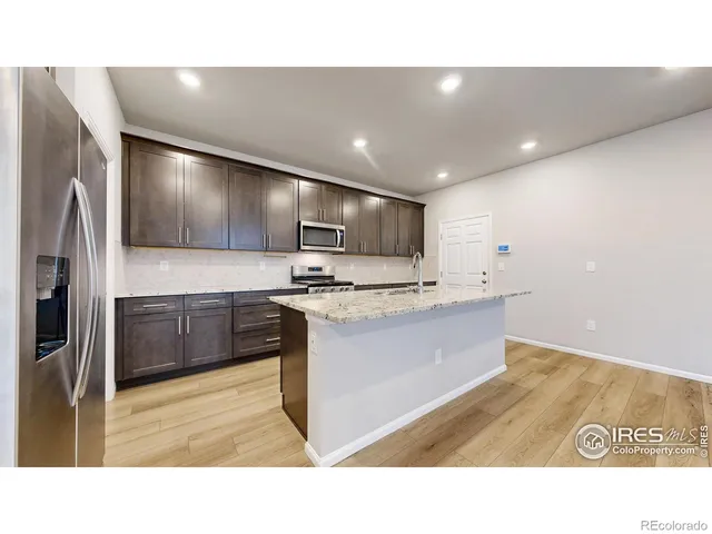 a kitchen with kitchen island granite countertop stainless steel appliances cabinets a sink and a counter top space