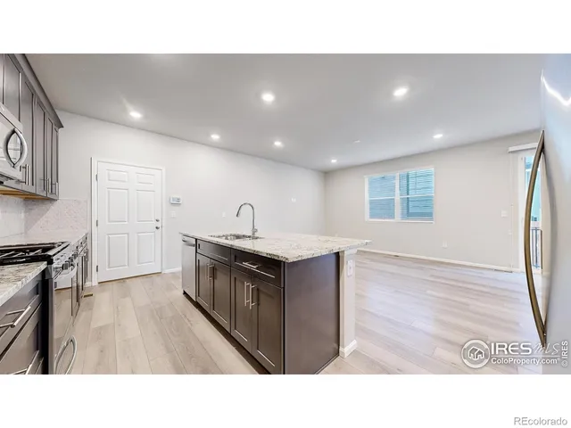 a open kitchen with kitchen island a sink wooden floor and black stainless steel appliances
