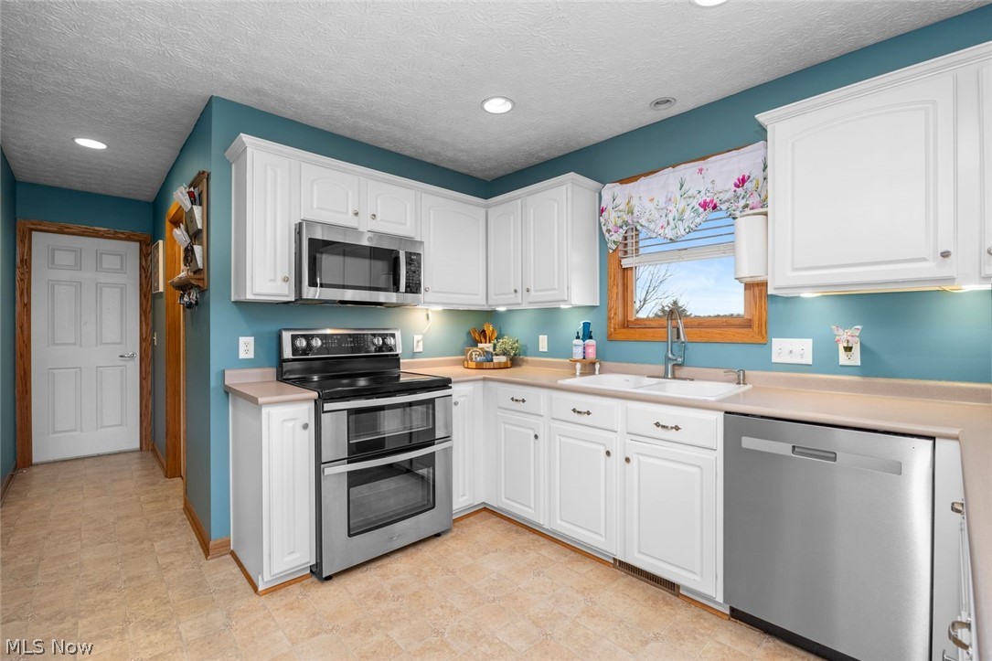 4273 Old State Road Willard, OH 44890 - Photo 5 of 50 Kitchen with stainless steel appliances, light countertops, white cabinets, recessed lighting, and a textured ceiling