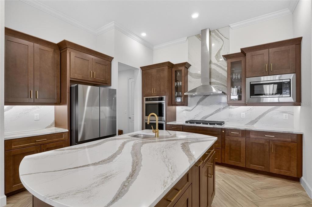 914 Signet Drive Apollo Beach, FL 33572 - Photo 25 of 100 a kitchen with kitchen island granite countertop wooden cabinets a sink and stainless steel appliances