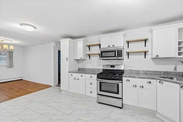 a kitchen with granite countertop white cabinets and stainless steel appliances
