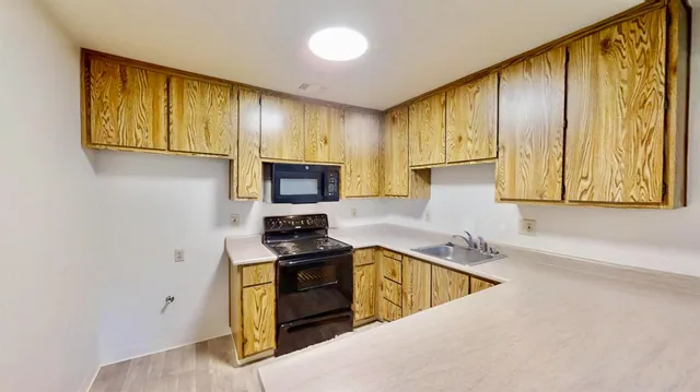 a kitchen with stainless steel appliances a stove a sink cabinets and a window