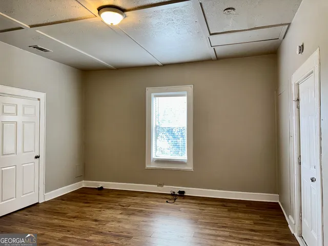 a view of an empty room with wooden floor and a window