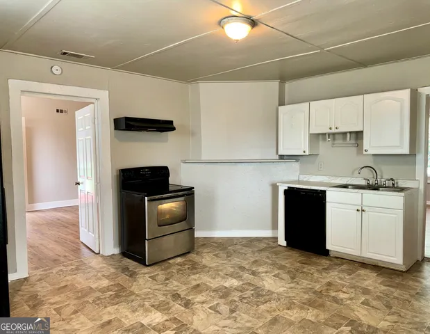 a kitchen with granite countertop a stove a sink and a refrigerator