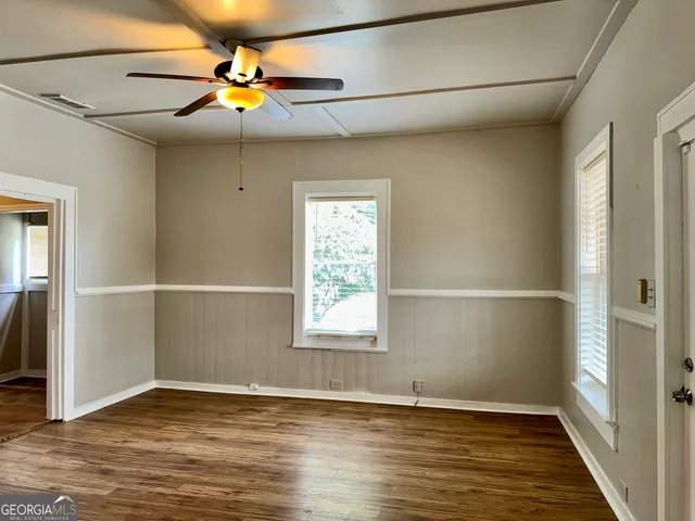a view of an empty room with a window and wooden floor