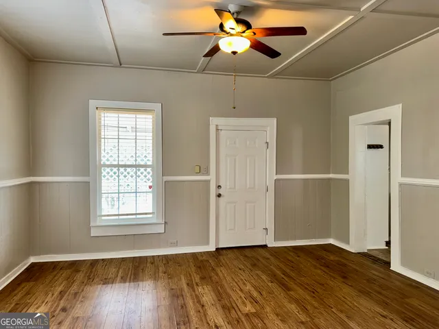 an empty room with wooden floor fan and windows