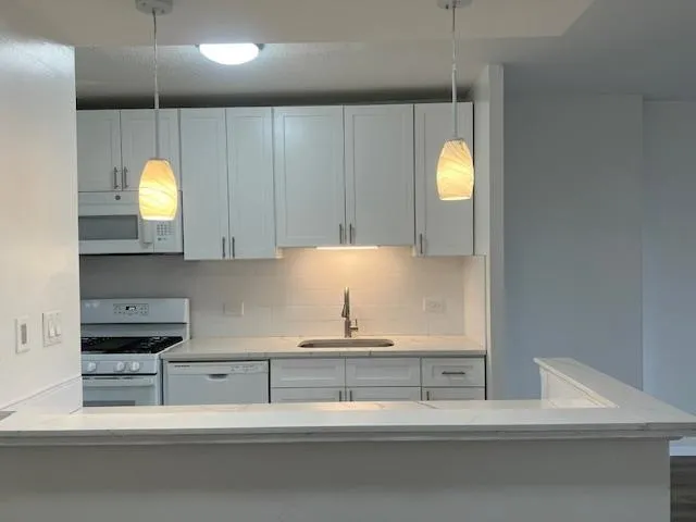 a kitchen with white cabinets a sink stove and refrigerator