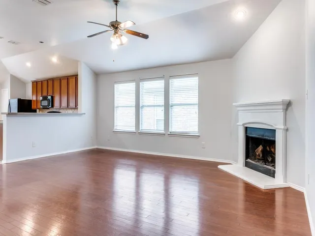 a view of empty room with wooden floor and a fireplace