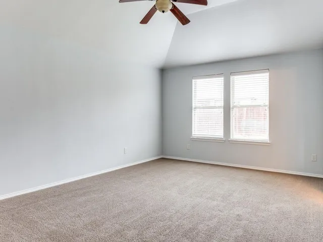 an empty room with ceiling fan and window