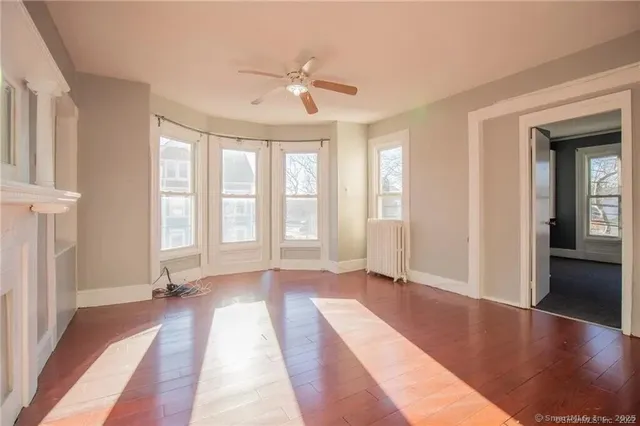 a view of an empty room with window and wooden floor
