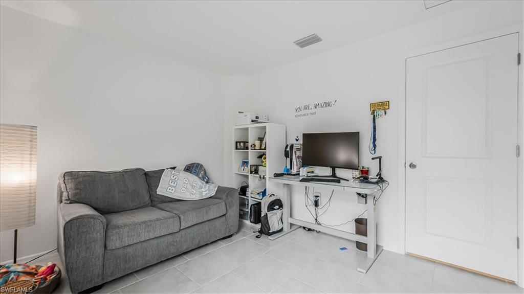 12252 Amber Waves Road Lehigh Acres, FL 33936 - Photo 25 of 35 a living room with furniture and a flat screen tv