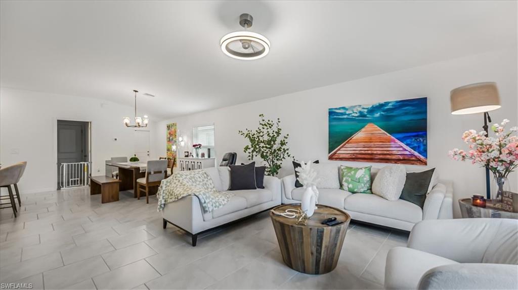12252 Amber Waves Road Lehigh Acres, FL 33936 - Photo 7 of 35 a living room with furniture and a chandelier