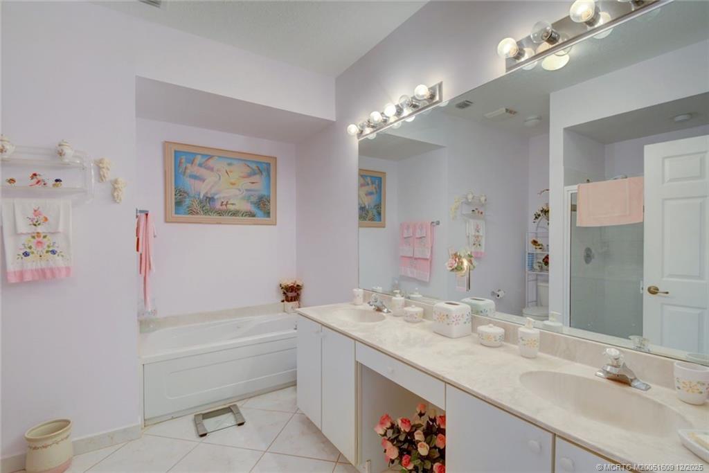 6789 Southeast Warwick Lane Stuart, FL 34997 - Photo 14 of 24 a bathroom with a tub a double vanity sink and a mirror