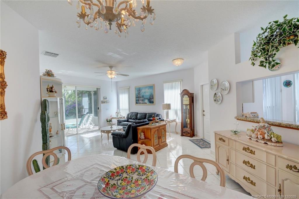 6789 Southeast Warwick Lane Stuart, FL 34997 - Photo 3 of 24 a living room with furniture a chandelier and a dining table