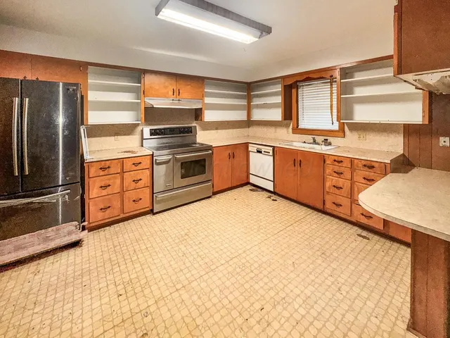 an empty room with chandelier fan and windows