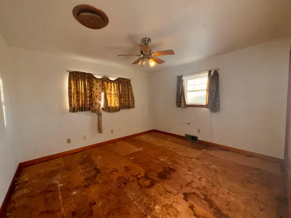 an empty room with windows and fan