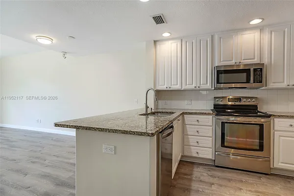 a kitchen with stainless steel appliances granite countertop a stove a microwave and white cabinets