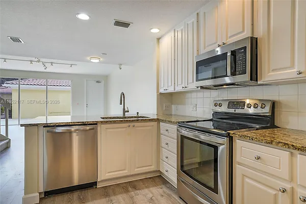 a kitchen with stainless steel appliances granite countertop a stove a sink and a microwave