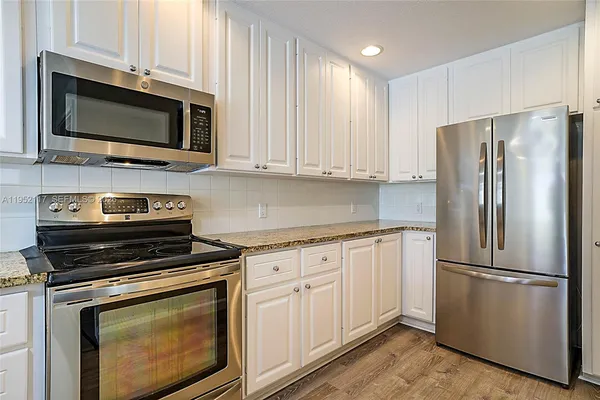 a kitchen with cabinets stainless steel appliances and wooden floor