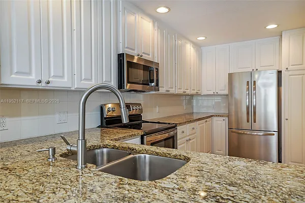 a kitchen with stainless steel appliances granite countertop a sink a stove a microwave and cabinets