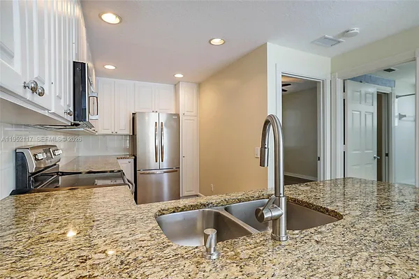 a kitchen with stainless steel appliances granite countertop a sink stove and refrigerator