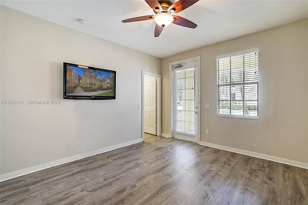 a view of an empty room with wooden floor and a window