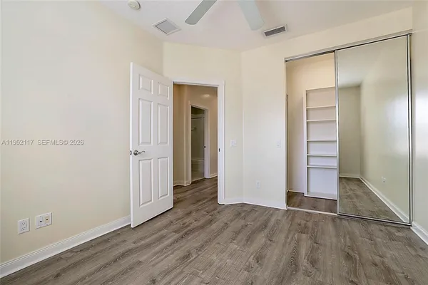 an empty room with wooden floor & closet and windows