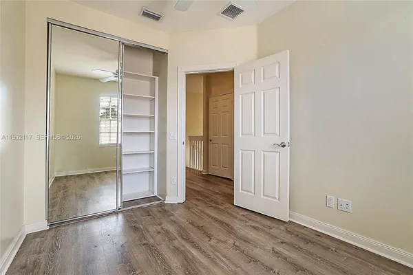 an empty room with wooden floor closet and windows