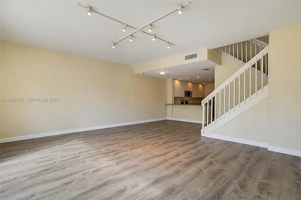 an empty room with wooden floor and staircase