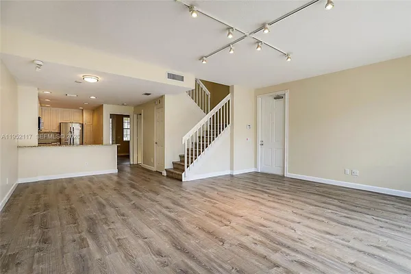 a view of an empty room with wooden floor and a ceiling fan