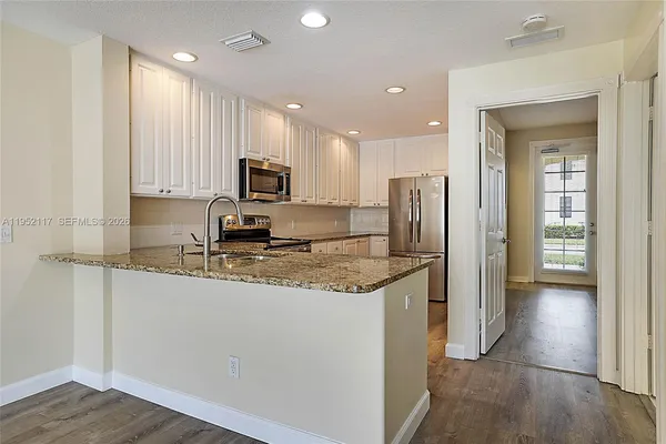 a kitchen with stainless steel appliances granite countertop a refrigerator sink and stove