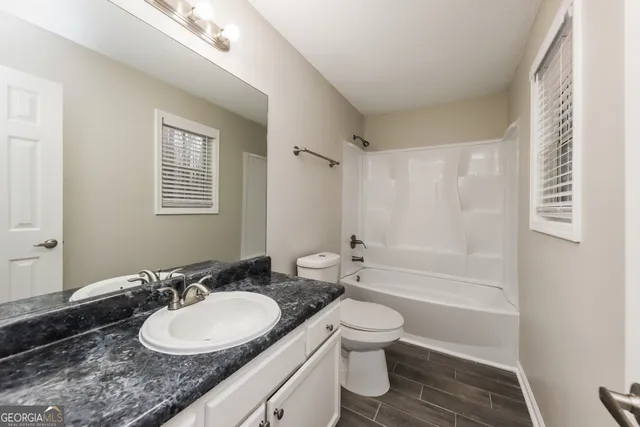 a bathroom with a granite countertop sink toilet a mirror and shower