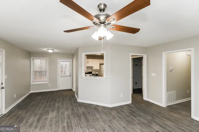 a view of empty room with wooden floor and ceiling fan