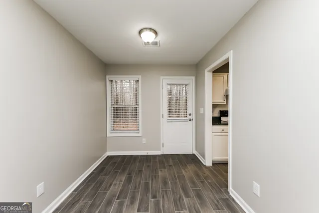an empty room with wooden floor and windows