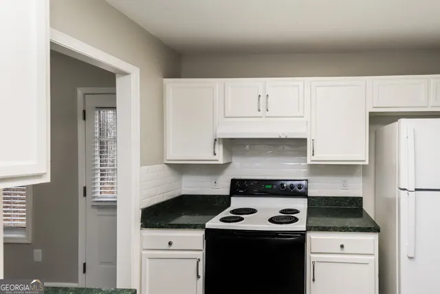 a kitchen with granite countertop a stove sink and cabinets