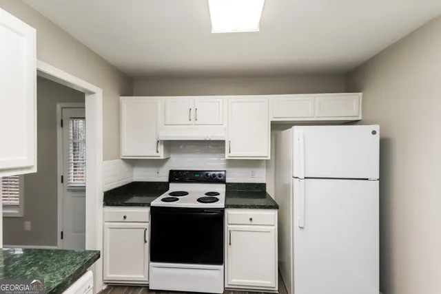 a kitchen with a refrigerator a stove a sink and white cabinets
