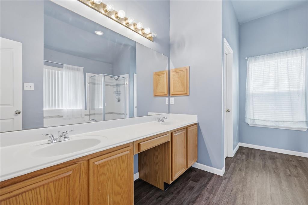 4545 Ridgepointe Drive The Colony, TX 75056 - Photo 25 of 37 Bathroom featuring a dual vanity with oak-finish cabinetry, a full-width mirror, and a glass-enclosed shower
