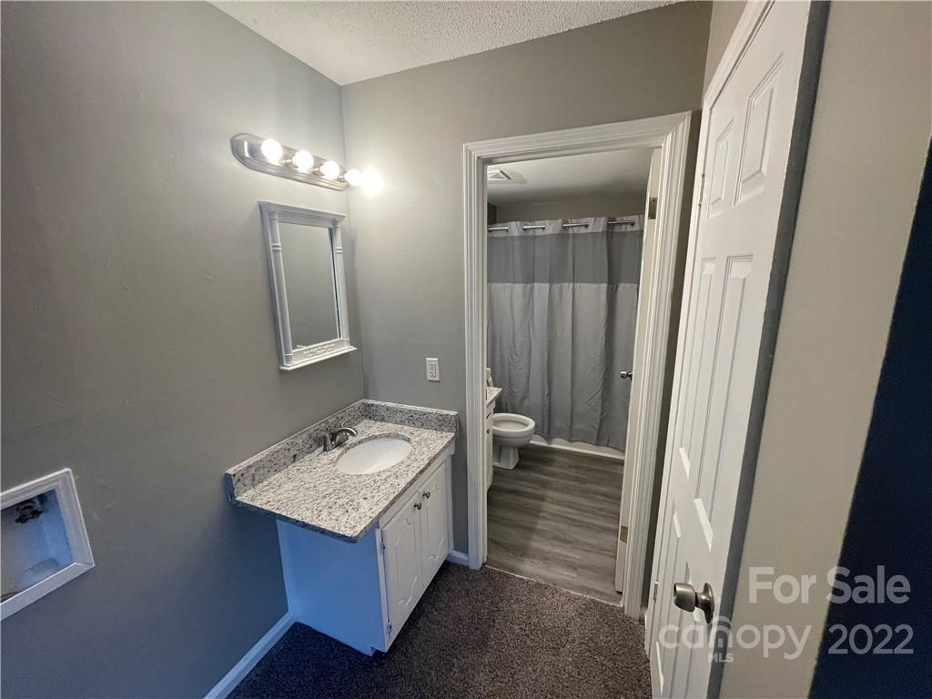 270 Spring Street Southwest Concord, NC 28025 - Photo 6 of 8 a bathroom with a granite countertop sink and a mirror