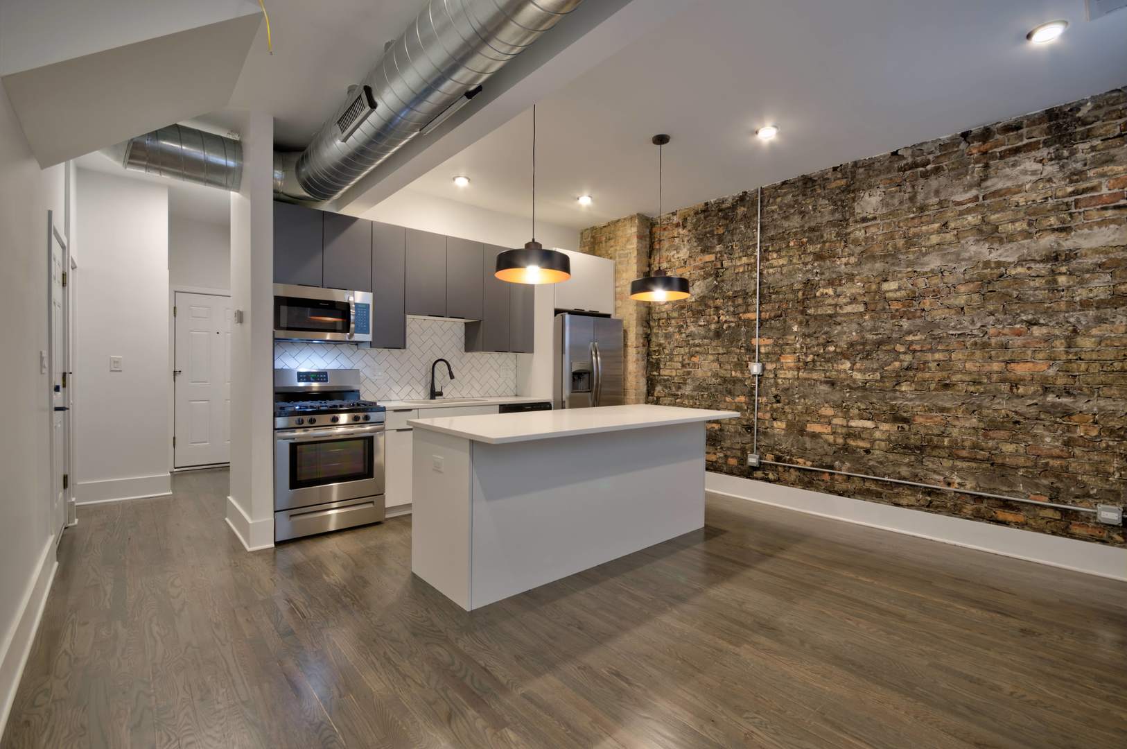 1917 South Racine Avenue, Unit 2F Chicago, IL 60608 - Photo 2 of 13 a large white kitchen with a refrigerator a stove a microwave and a dining table with wooden floor