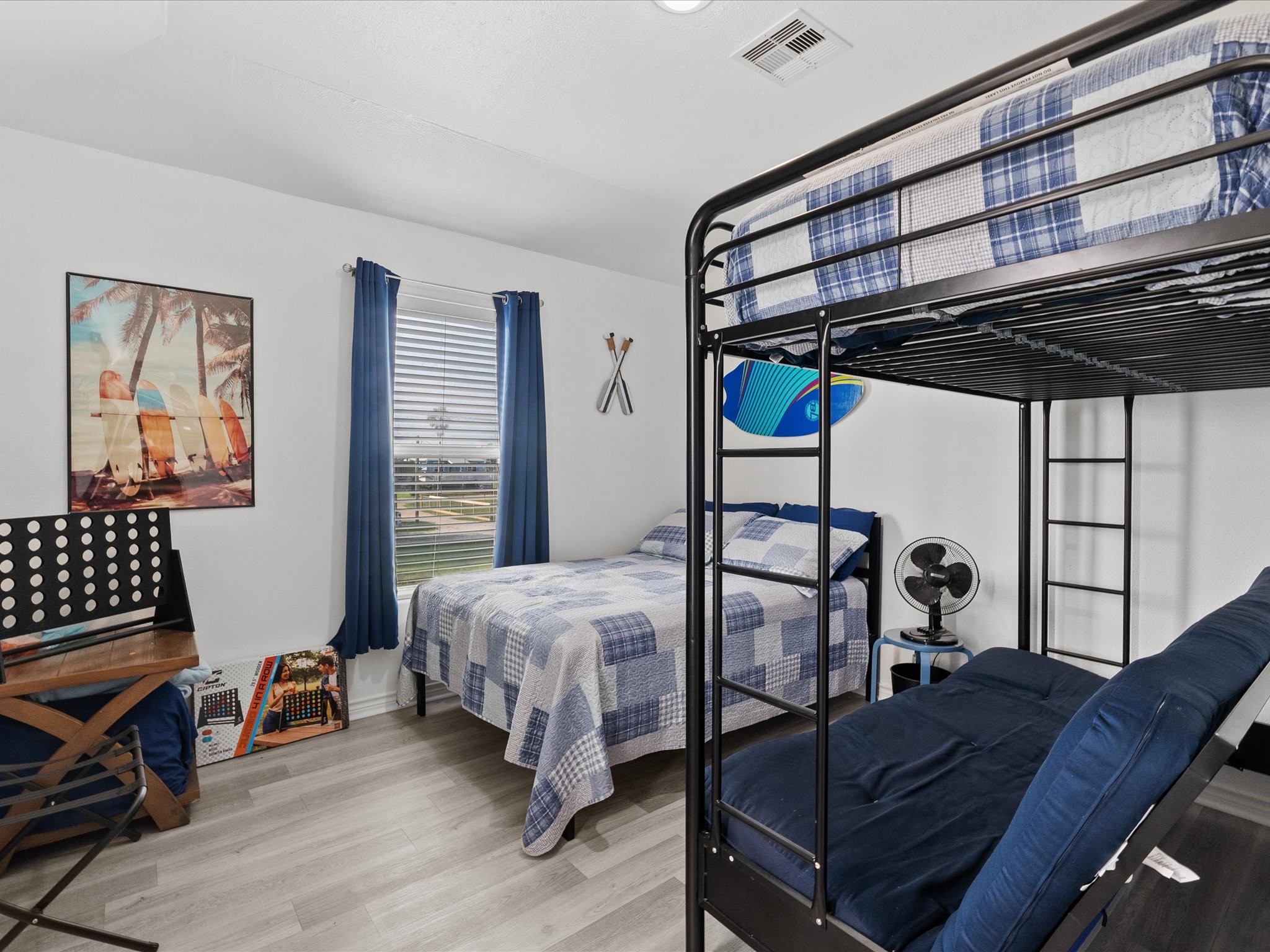 818 Surf Drive Surfside Beach, TX 77541 - Photo 17 of 29 This bedroom features a bunk bed with a twin over a futon, a separate twin bed, and playful decor. The room is bright with natural light, laminate flooring, and a surf-themed vibe, ideal for kids or guests.