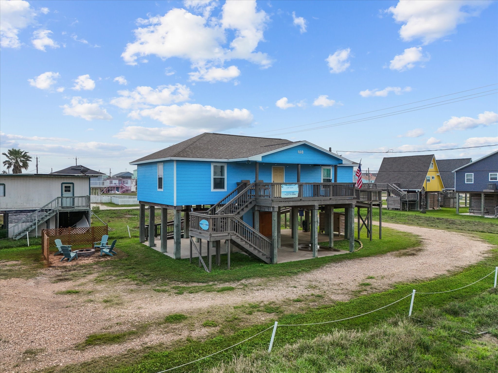 818 Surf Drive Surfside Beach, TX 77541 - Photo 3 of 29 This blue beach house features a spacious wraparound deck, ample parking underneath, and is surrounded by a grassy yard. Ideal for coastal living, it offers a relaxed outdoor seating area and easy access to nearby amenities.