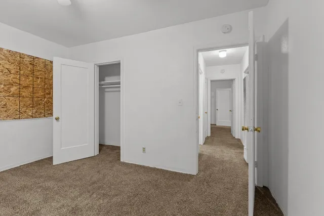 an empty room with wooden floor chandelier fan and windows