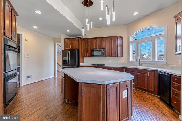 a kitchen with stainless steel appliances granite countertop wooden cabinets a sink and a window