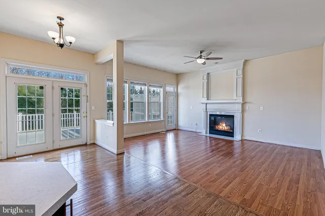 a view of an empty room with wooden floor fireplace and a window