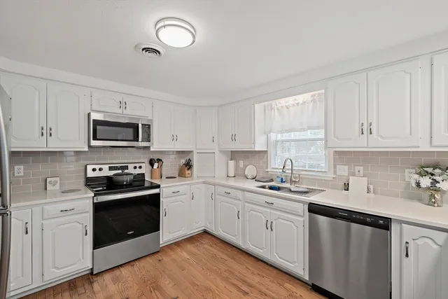 a kitchen with white cabinets stainless steel appliances and sink