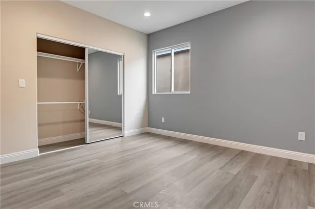 a view of an empty room with wooden floor & closet