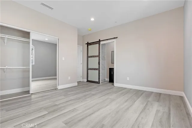 an empty room with wooden floor & closet area