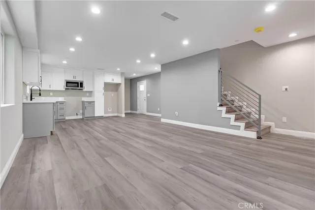 a view of a kitchen with kitchen island a sink wooden floor and stainless steel appliances