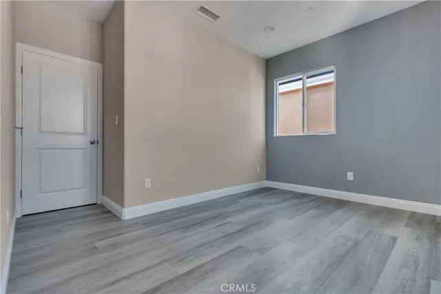 a view of an empty room with wooden floor and closet